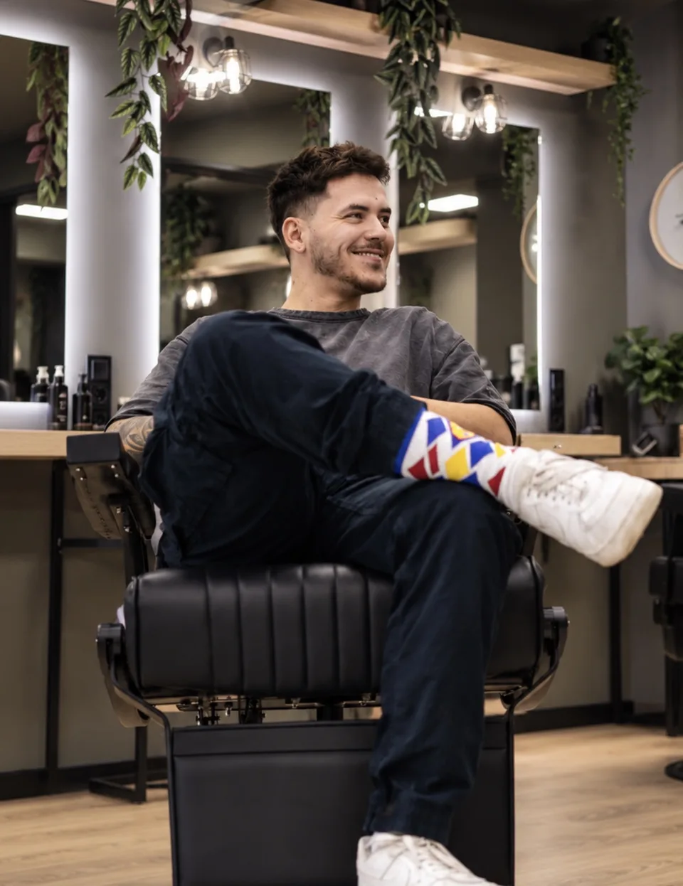 Bence, a Beautyflow for Men barbere mosolyogva ül a barber székben a szalon tükrei előtt
